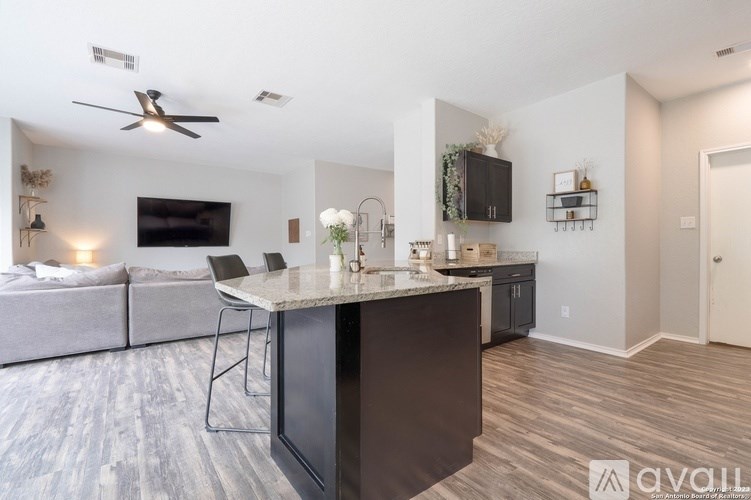 A modern kitchen with a black island and a grey couch in the background.