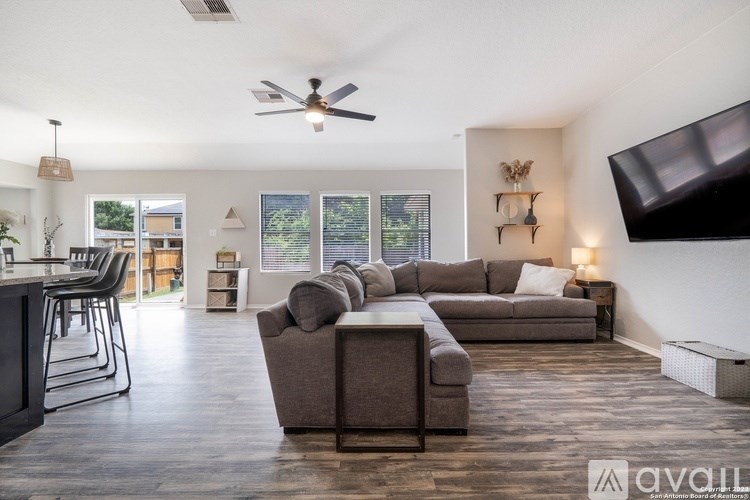 A living room with a grey couch and a ceiling fan.