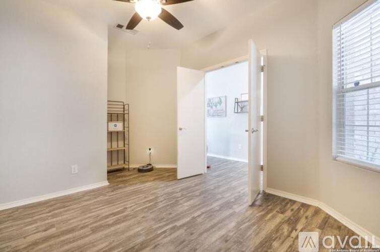 A room with a ceiling fan and a door leading to another room.