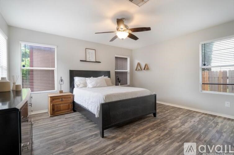 A bedroom with a bed, nightstand, and a ceiling fan.