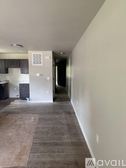 A room with a kitchen area in the background and a doorway leading to another room.