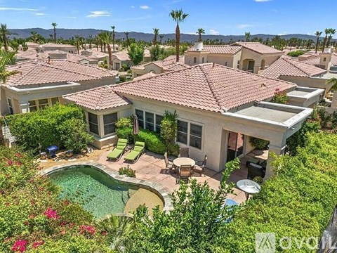 A house with a pool surrounded by greenery and palm trees.