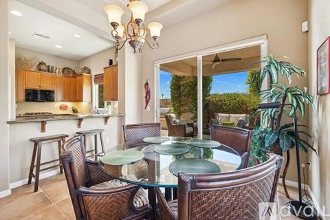 A dining room with a glass table and brown chairs.