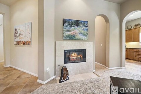 A living room with a fireplace and a painting of a forest scene on the wall.