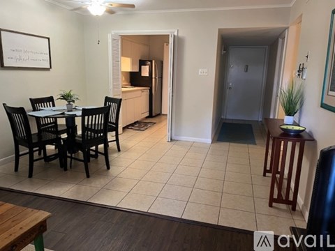 A dining room with a table set for four and a kitchen in the background.