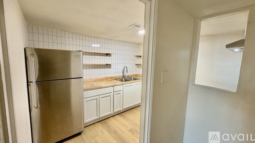 A kitchen with a stainless steel refrigerator and white cabinets.