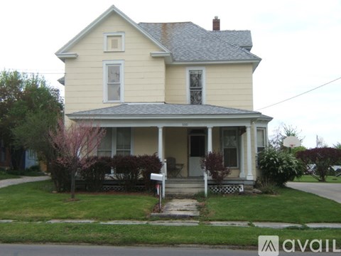 A two-story house with a front porch and a mailbox.