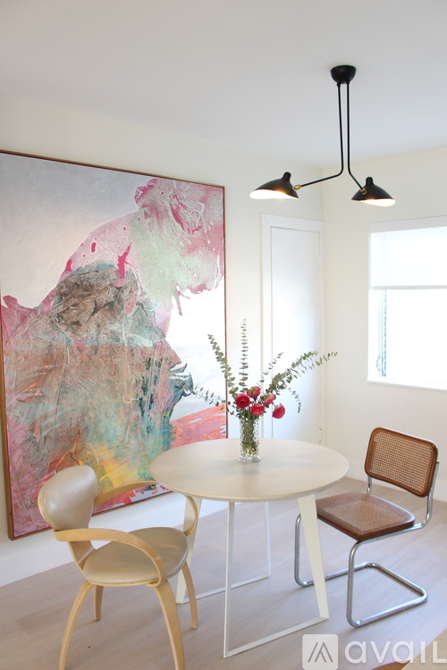 A living room with a white couch, a wooden chair, and a glass table.