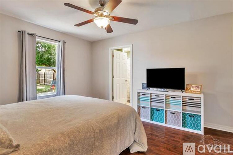 A bedroom with a bed, a television, and a ceiling fan.