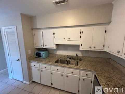A kitchen with white cabinets and a granite countertop.