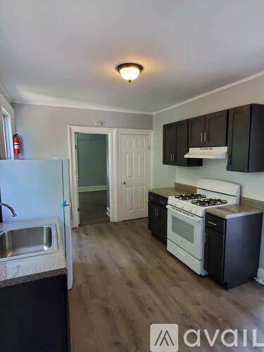 A kitchen with a white fridge, black cabinets, and a white stove.
