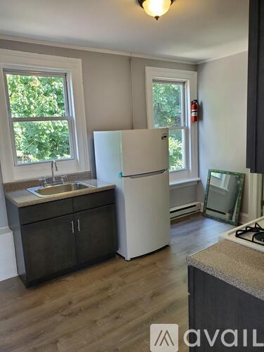 A kitchen with a white fridge and wooden floors.
