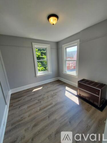 A room with wooden flooring and a window overlooking a red building.