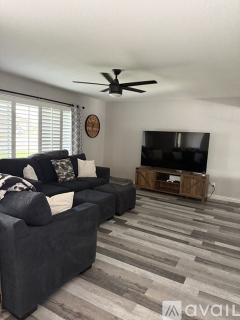 A living room with a grey couch and a wooden entertainment center.
