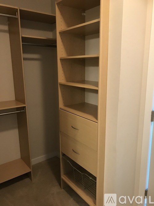 A white closet with shelves and drawers is open.