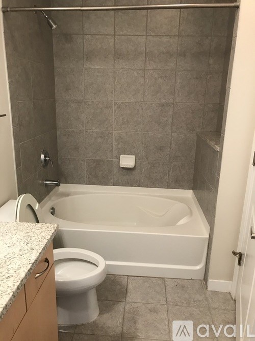A bathroom with a toilet, tub, and tiled walls.