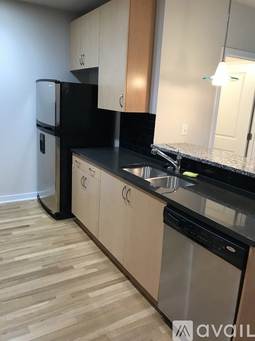 A kitchen with wooden floors and black countertops.