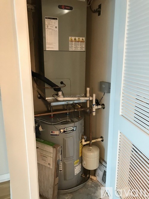 A view of a utility room with a water heater and a furnace.