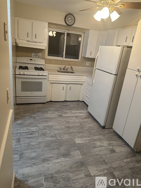 A kitchen with white appliances and cabinets.