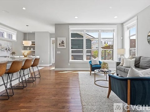 A modern living room with a grey couch, a coffee table, and a dining table with chairs.