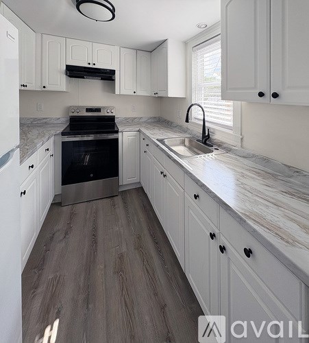 A kitchen with white cabinets and a marble countertop.