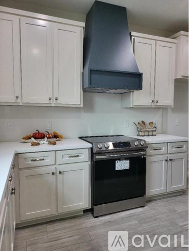 A kitchen with white cabinets and a black range hood.
