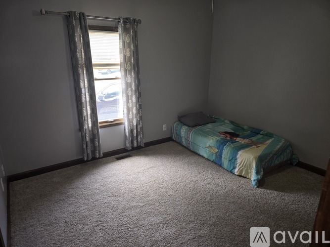 A bedroom with a bed and a window with curtains.