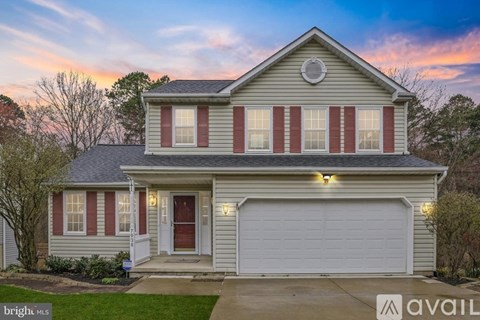 A house with a red door and garage door is for sale.