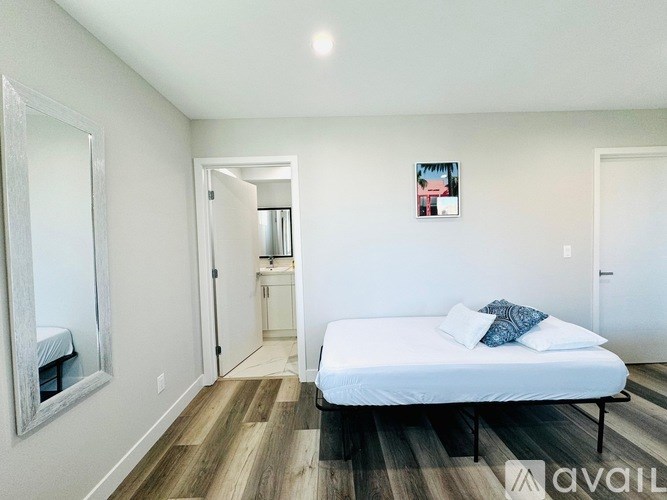 A bedroom with a bed, a mirror, and a picture on the wall.