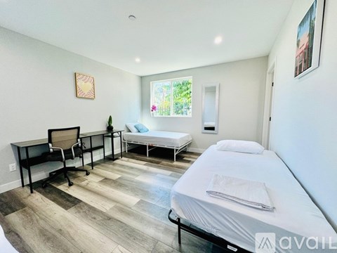 A bedroom with a bed, desk, and chair.