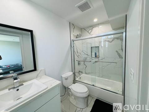 A bathroom with a toilet, sink, and mirror.