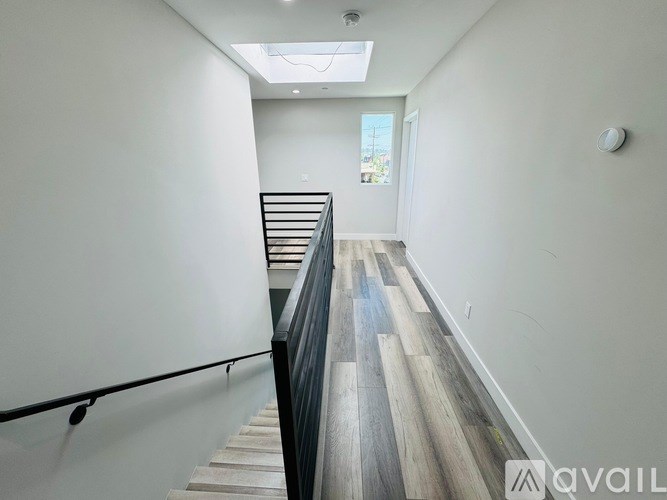 A hallway with a skylight and a staircase with a black railing.