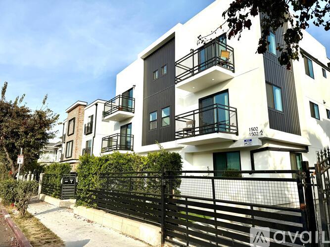 A modern two-story building with balconies and a black gate.