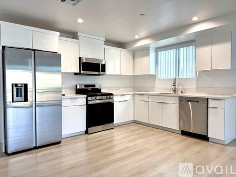 A modern kitchen with white cabinets and stainless steel appliances.