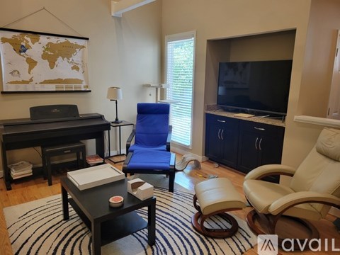 A living room with a blue chair and a black piano.