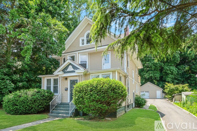 A house with a front yard and a tree branch hanging over the front door.