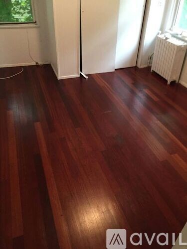 A room with wooden flooring and a window with curtains.