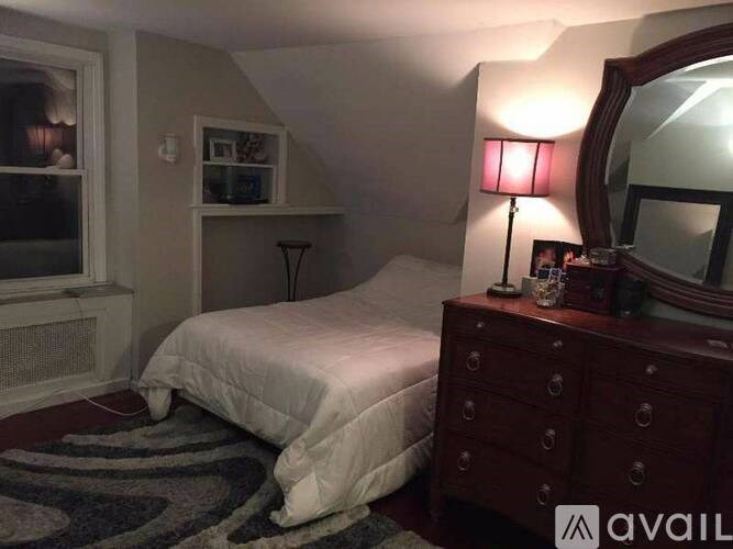 A bedroom with a bed, dresser, and mirror.
