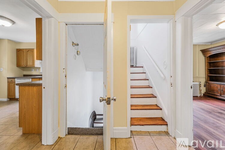 A hallway with a staircase and a door leading to another room.