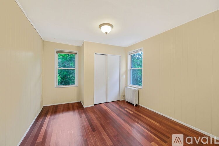A room with wooden floors and two windows.