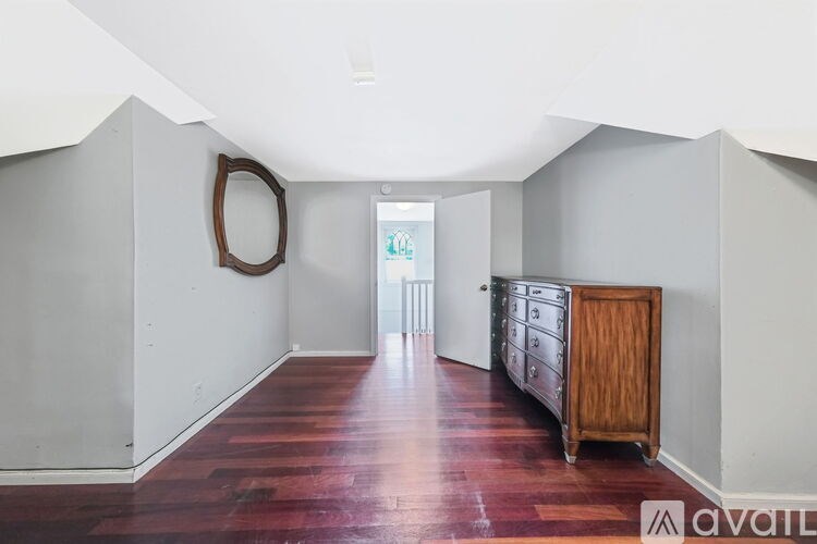 A hallway with a wooden floor and a mirror on the wall.