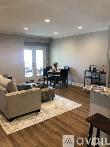 A living room with a couch, chairs, and a table with a vase of flowers on it.