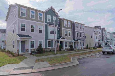 A row of houses with a car parked in front of them.