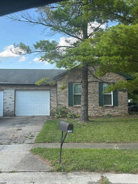 A brick house with a white garage door and a mailbox.