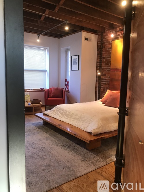 A bedroom with a bed, chair, and a rug.