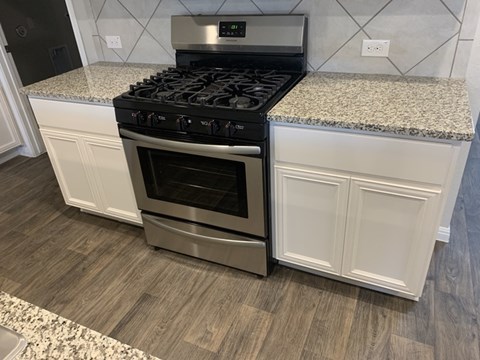 A modern kitchen with a stainless steel oven and a granite countertop.