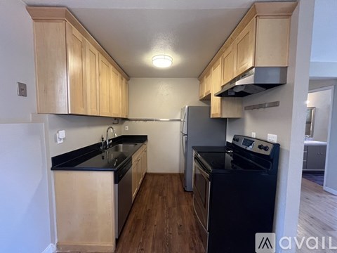 A kitchen with wooden cabinets and black countertops.