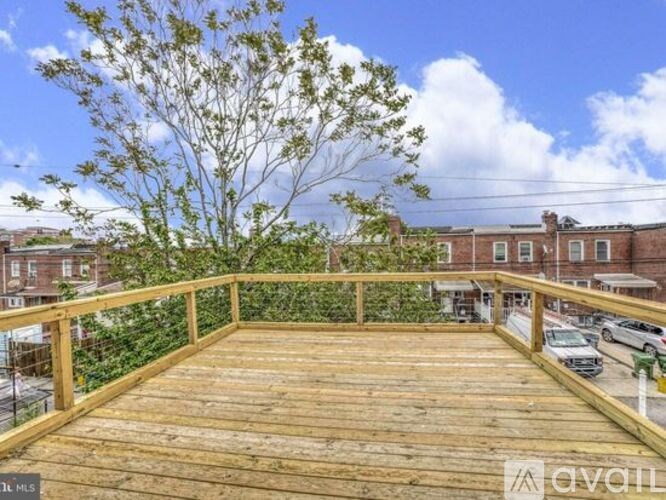 A wooden deck with a tree in the background and cars parked in the distance.