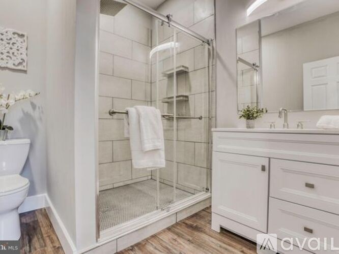 A white bathroom with a glass shower door and a towel hanging on the door.