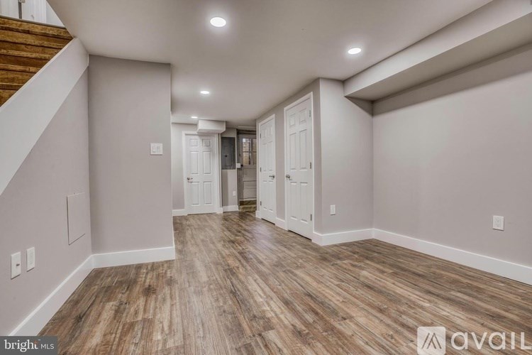A spacious room with wooden flooring and white walls.